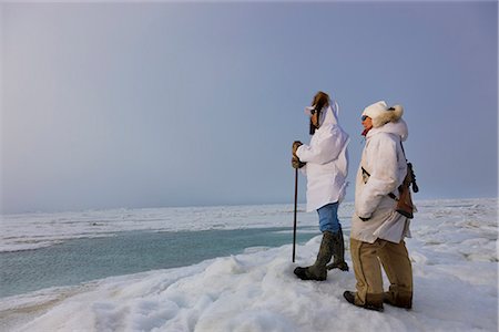 Two Eskimos standing and looking at horizon.
