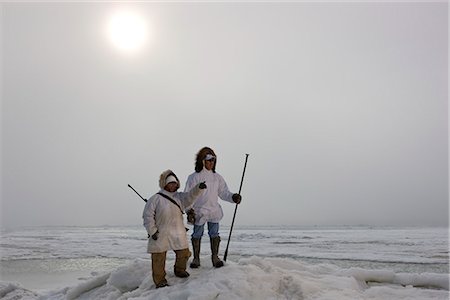 Two Eskimos standing and pointing.