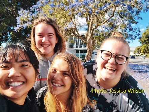 Four happy teenage girls, smiling at camera on a sunny day.