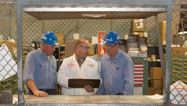 Three workmen discussing work document.