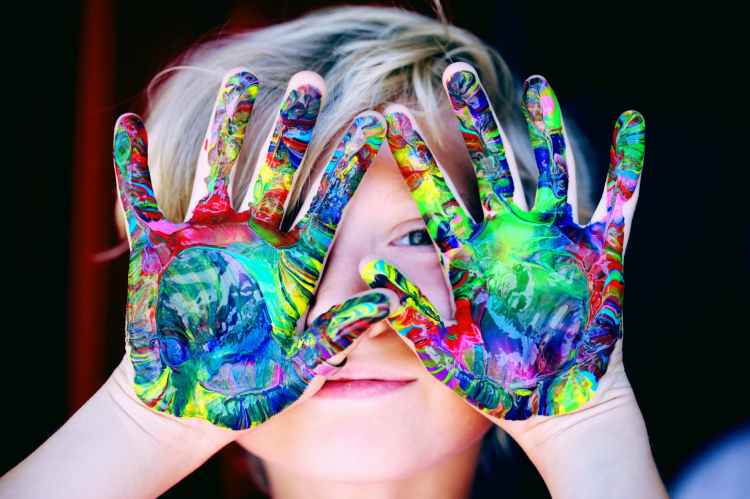 Happiness image of a child with paint all over the palms of their hands.