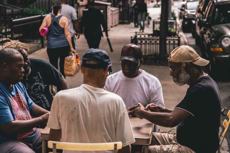 Group of men sitting outdoors around a table.