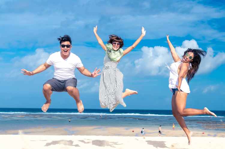 Happiness image of three young people jumping in the air at a beach.